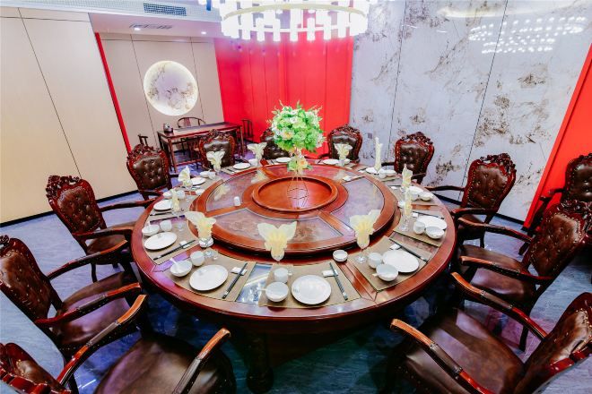 Una mesa de comedor redonda con sillas, un arreglo floral central y una araña.