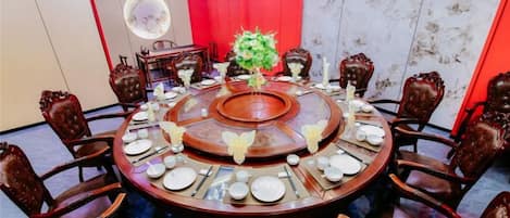 A round dining table with chairs, a central floral arrangement, and a chandelier.