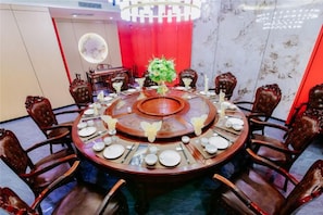 A round dining table with chairs, a central floral arrangement, and a chandelier. - Jintai Hotel (Tongguan)