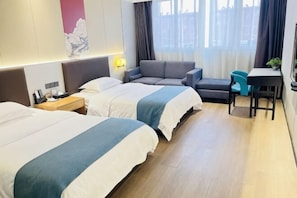 Une chambre d’hôtel avec deux lits, un canapé, un bureau et une chaise.