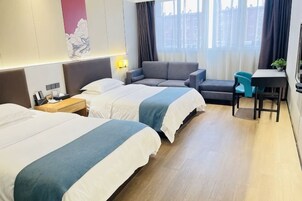 Habitación de hotel con dos camas, un sofá, un escritorio y una silla.