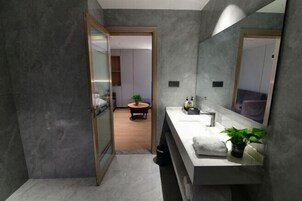 Un baño moderno con un espejo grande, una encimera blanca y una planta en maceta.