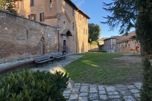 A courtyard with a brick building, a bench, and a small garden area. - CASA ILARIA - Bright apartment with a view in the historic center (Siena)
