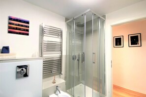 A modern bathroom with a glass-enclosed shower, a white sink, and a towel rack. - CASA ILARIA - Bright apartment with a view in the historic center (Siena)