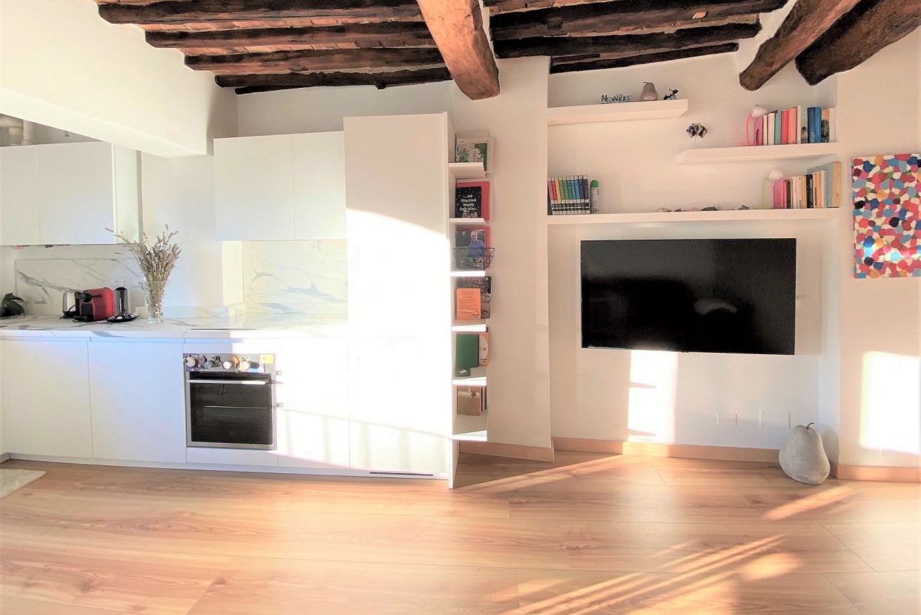 Una cocina moderna con armarios blancos, horno empotrado y un ventanal amplio.