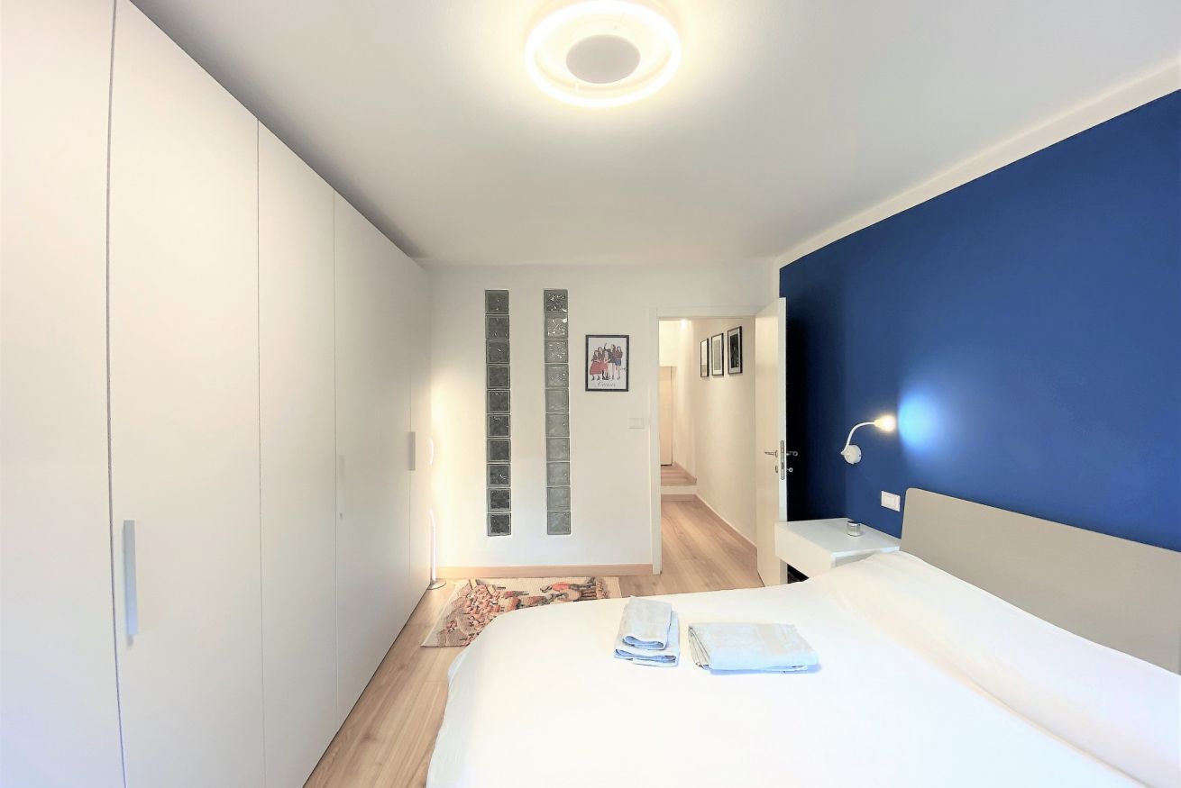 Une chambre d’hôtel moderne avec un grand lit, une table de chevet, un bureau et un mur d’accent bleu.
