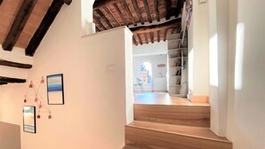 A staircase with wooden steps leading to a room with a white wall and a ceiling with exposed beams. - CASA ILARIA - Bright apartment with a view in the historic center (Siena)