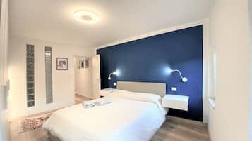Una camera da letto moderna con un letto grande, lampade sui comodini e una parete d'accento scura.