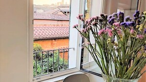 A balcony with a view of buildings and a vase of flowers. - CASA ILARIA - Bright apartment with a view in the historic center (Siena)