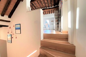 A staircase with wooden steps leading to a room with a white wall and a ceiling with exposed beams. - CASA ILARIA - Bright apartment with a view in the historic center (Siena)