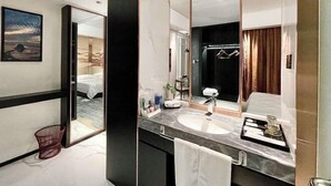A modern hotel bathroom with a large mirror, a marble sink, and a separate shower area. - Chenxi International Hotel (Xiapu)