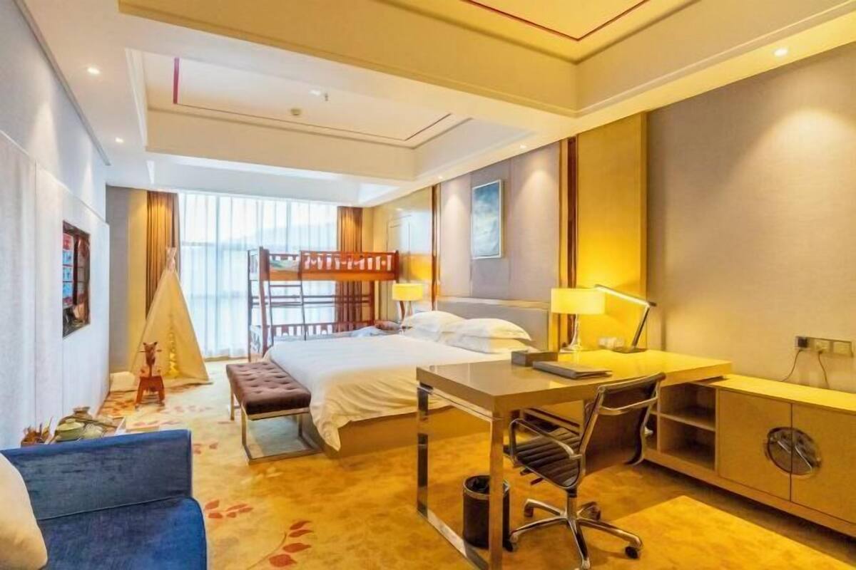 A hotel room with a bed, desk, chair, and a small table.