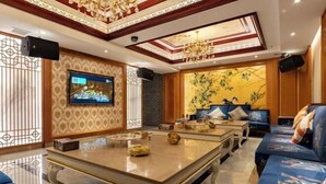 A spacious living room with a large TV, a sofa set, and a decorative wall mural. - Chenxi International Hotel (Xiapu)