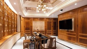 A modern interior with a wooden dining table, chairs, a large flat-screen TV, and a decorative ceiling. - Chenxi International Hotel (Xiapu)
