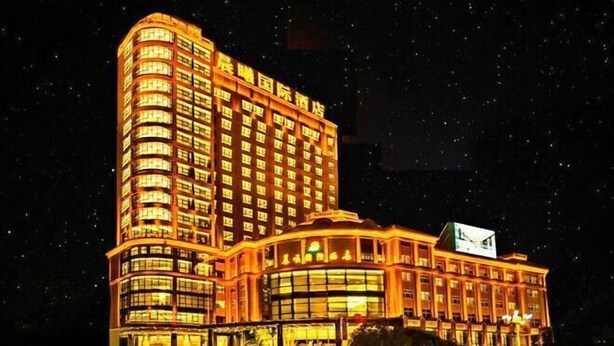 A multi-story hotel with a curved facade and illuminated windows. - Chenxi International Hotel (Xiapu)