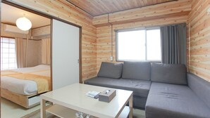 Ein Zimmer mit einem Bett, einem Sofa, einem Tisch und einem Fenster mit Vorhängen.