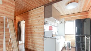 Ein Zimmer mit Holzwänden, einer Küchenzeile, einer steilen Treppe und einem großen Fenster.