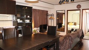 Ein Hotelzimmer mit Essbereich, Fernseher, Bett und einem durchgegangenen Tür erkennbaren Badezimmer.