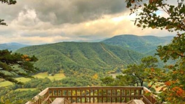 Una terraza de madera con vista a un paisaje montañoso.