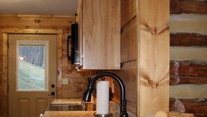 Una cocina con encimera de granito, pileta de acero inoxidable, armarios de madera y una puerta de madera con ventanal.