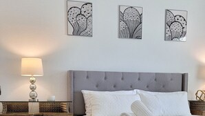 Une chambre à coucher comprenant un lit, une table de chevet, une lampe et des éléments décoratifs sur les murs.