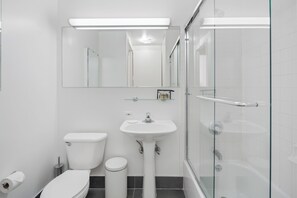 Une salle de bain moderne équipée de toilettes, d’un lavabo et d’une douche à parois de verre.