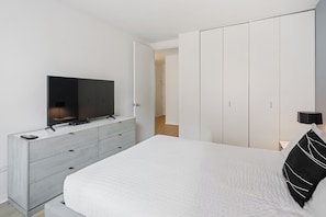 A bedroom with a bed, a TV on a dresser, and a wardrobe.