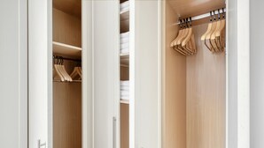A walk-in closet with wooden doors, a hanging rod, and shelves. - Compact Covent Garden 2BR, 1 min to Embankment station, by Blueground (London)
