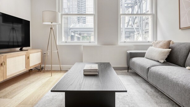A modern living room with a large TV, a wooden cabinet, a floor lamp, a grey sofa, and a coffee table. - Compact Covent Garden 2BR, 1 min to Embankment station, by Blueground (London)