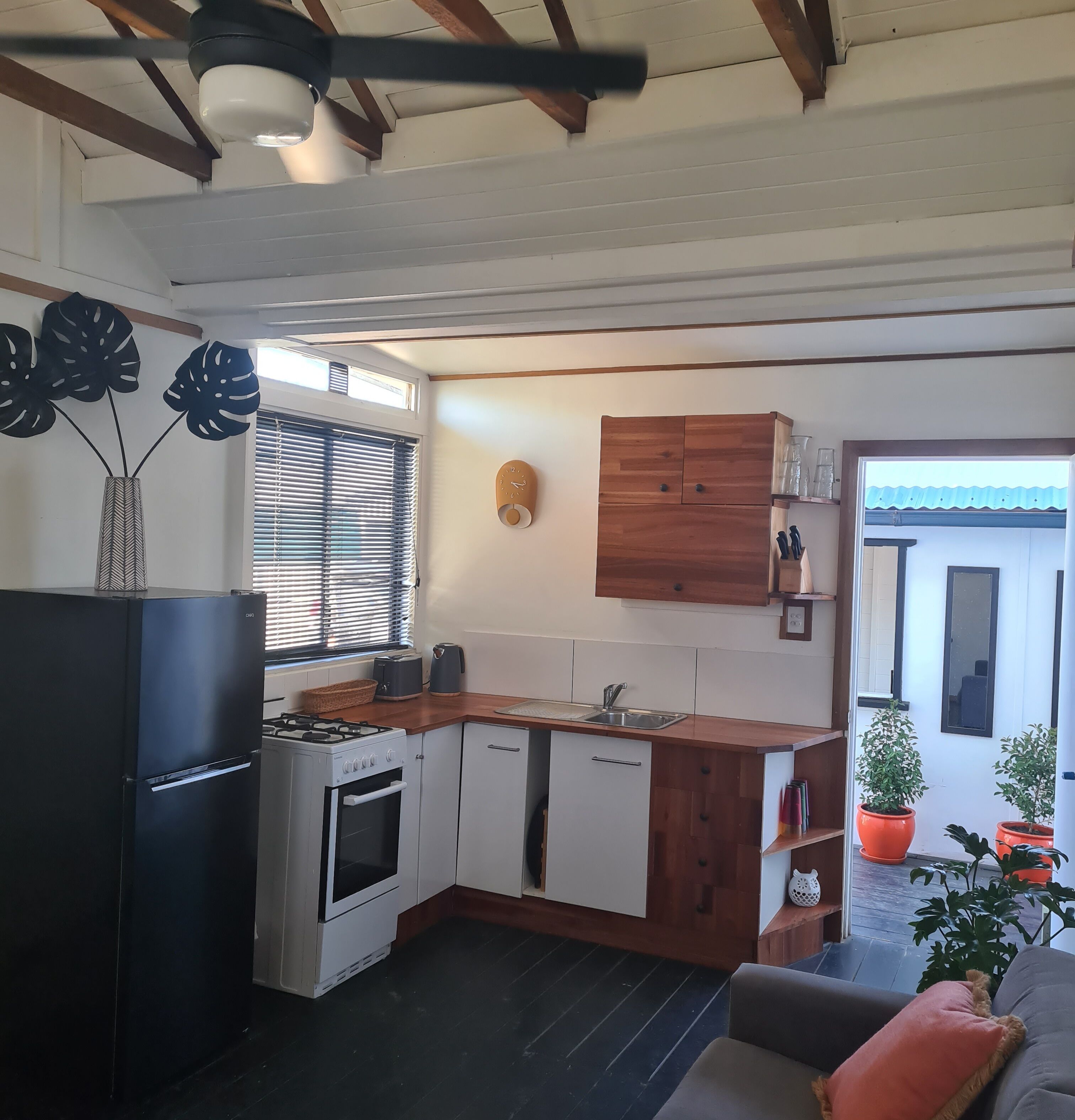 A modern kitchen with a gas stove, oven, and a built-in dishwasher. There is a window with blinds, a wooden cabinet, and a small sink.