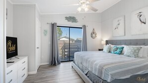 A bedroom with a bed, a TV, a ceiling fan, and a view of the outside. - Pet Friendly | Remodeled | Private Backyard | FLPCB37 (Panama City Beach)