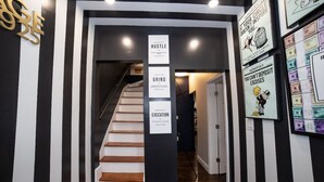 Eine Treppe mit schwarz-weiß gestreiften Wänden, einem hölzernen Geländer und drei Schildern mit den Aufschriften „HUSTLE“, „GRIND“ und „EXECUTION“.