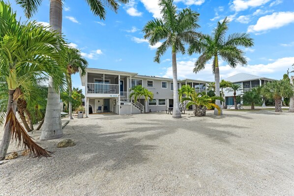 A beachfront hotel with a two-story structure, a covered outdoor area, and palm trees.