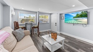 Una sala de estar moderna con un sofá, una mesa de centro y un televisor instalado en la pared, con vistas a la playa.