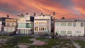 A modern multi-story residential building with a balcony, large windows, and a flat roof. - Beachfront Sunset Beach, Ocean Views, Sleeps 10 (Huntington Beach)