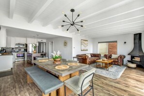 A spacious living area with a dining table, leather sofas, and a fireplace. - Beachfront Sunset Beach, Ocean Views, Sleeps 10 (Huntington Beach)