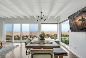 A dining area with a table, chairs, and a view of the beach.