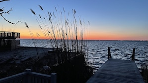 A wooden pier leading to a beach with tall grasses and a sunset in the background. - Beach house Davis Park, Fire Island  (brookhaven)