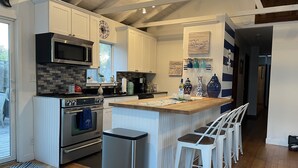 A modern kitchen with white cabinetry, a built-in oven, a microwave, and a stainless steel range hood. - Beach house Davis Park, Fire Island  (brookhaven)