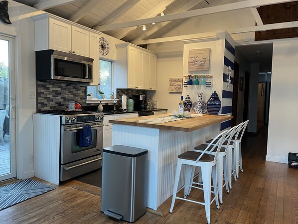 A modern kitchen with white cabinetry, a built-in oven, a microwave, and a stainless steel range hood.
