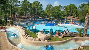 A water park with multiple pools and slides, surrounded by trees and a clear sky. - BEACHFRONT Condo! FREE BEACH SERVICE! Sleeps 8! 2Bed 2Bath + Sleeper (Panama City Beach)