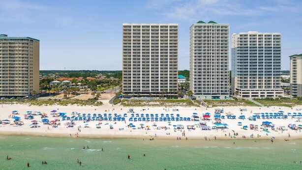A beachfront hotel with multiple high-rise buildings, a sandy beach with numerous umbrellas, and clear blue skies. - BEACHFRONT Condo! FREE BEACH SERVICE! Sleeps 8! 2Bed 2Bath + Sleeper (Panama City Beach)