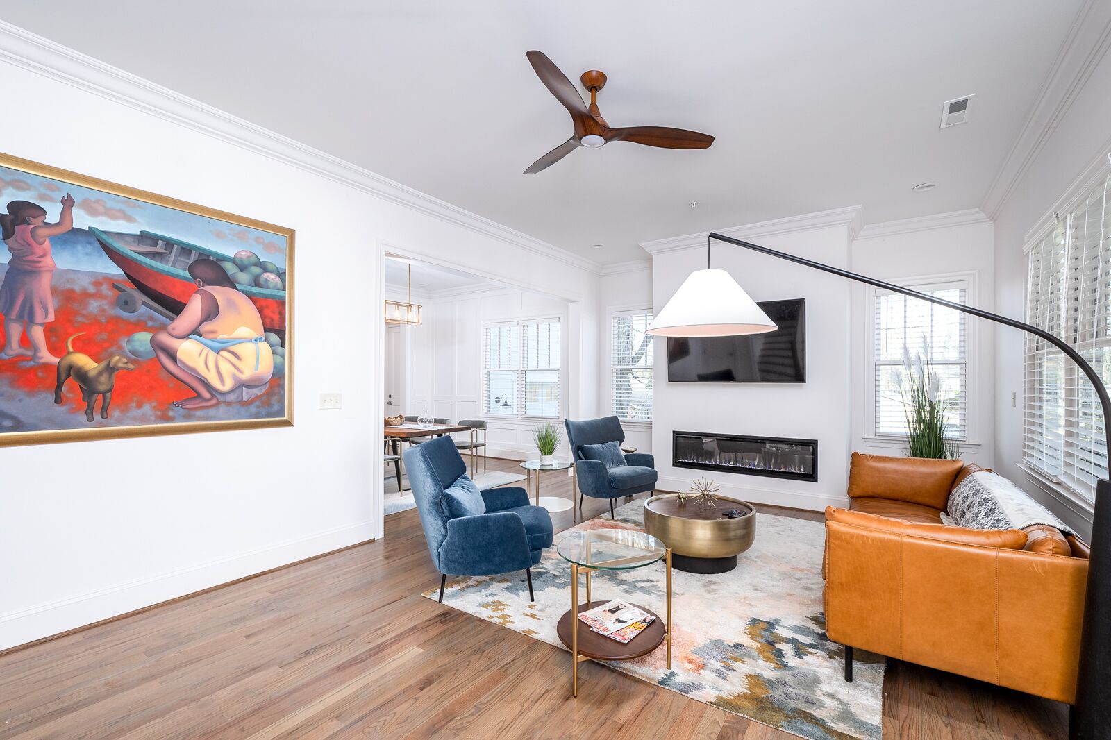 A spacious living room with a modern fireplace, a large painting on the wall, and a ceiling fan.