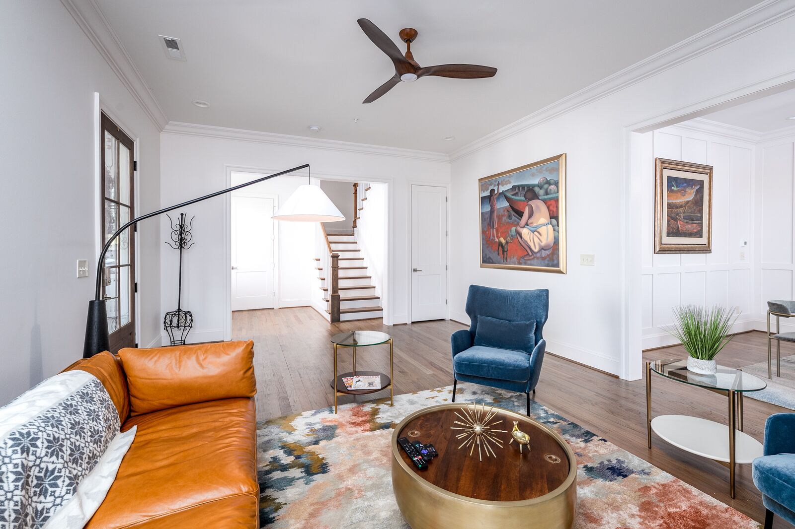 Un salon moderne avec un canapé, un fauteuil, une table basse et des œuvres d’art accrochées aux murs.