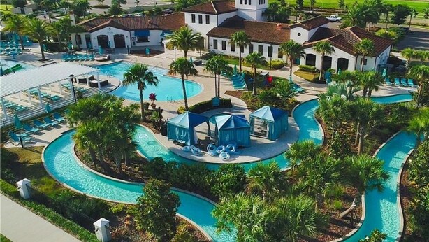Ein Resort mit großem Schwimmbad, Palmen und einem Clubhaus.