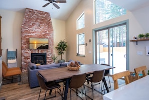 A cozy living area with a brick fireplace, a large dining table, and comfortable seating.