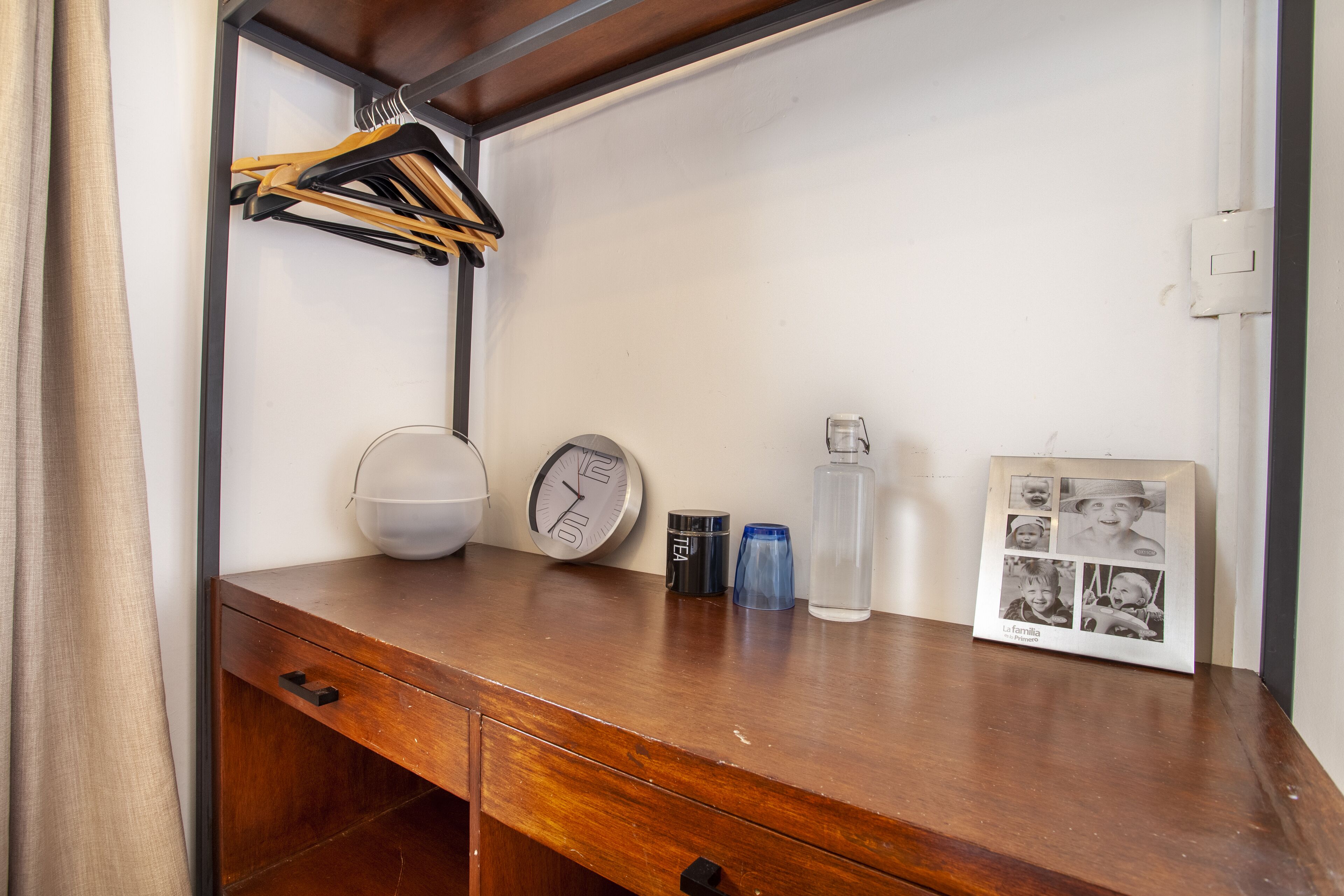 A wooden desk with a clock, a framed photo, a water bottle, and a cup.