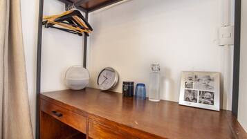 A wooden desk with a clock, a framed photo, a water bottle, and a cup.