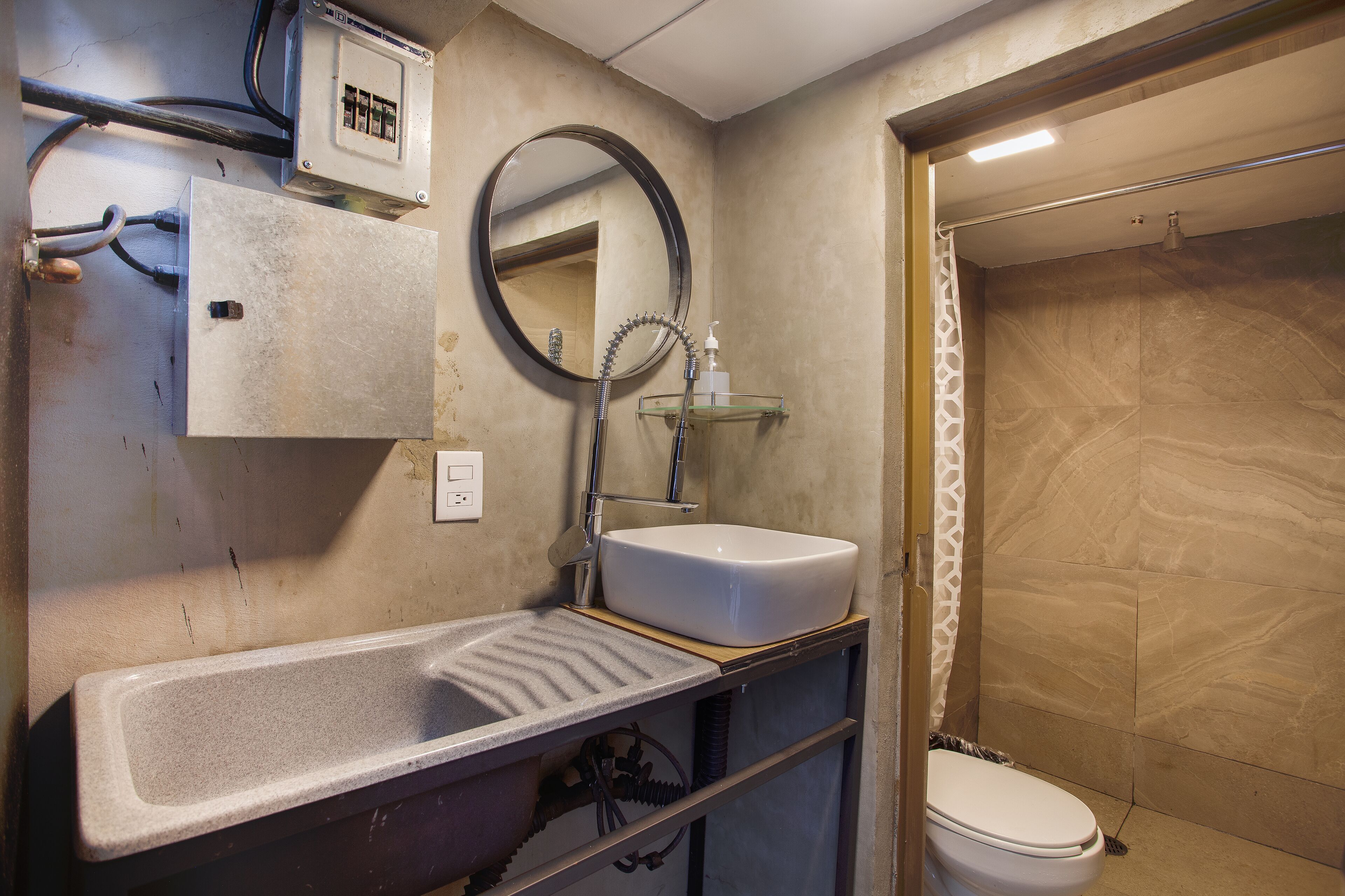 A bathroom with a rectangular sink, a mirror, a toilet, and a shower area.