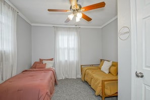 Un dormitorio con una cama individual, un sofá, un ventilador de techo y una puerta con un letrero.